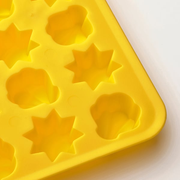 Bright yellow ice tray with star-shaped molds on white surface.