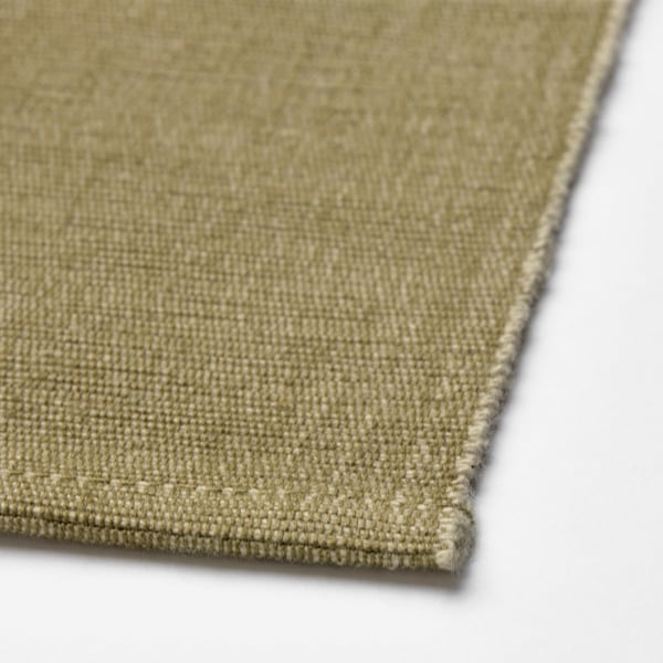 Corner of light green woven fabric with neat stitching, displaying fine texture and quality
