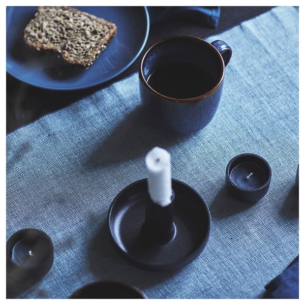 SVARTSENAP blue table runner with white candle, cup, and food on table.