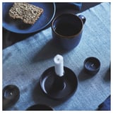 SVARTSENAP blue table runner with white candle, cup, and food on table.