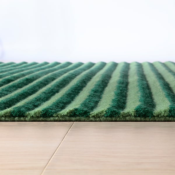 Stylish, textured striped rug, likely hand-tufted with high and low piles, creating 3d effect. Dark and light green hues.