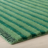 Stylish green striped rug with textured 3d effect, showcasing high quality wool craftsmanship on wooden floor.