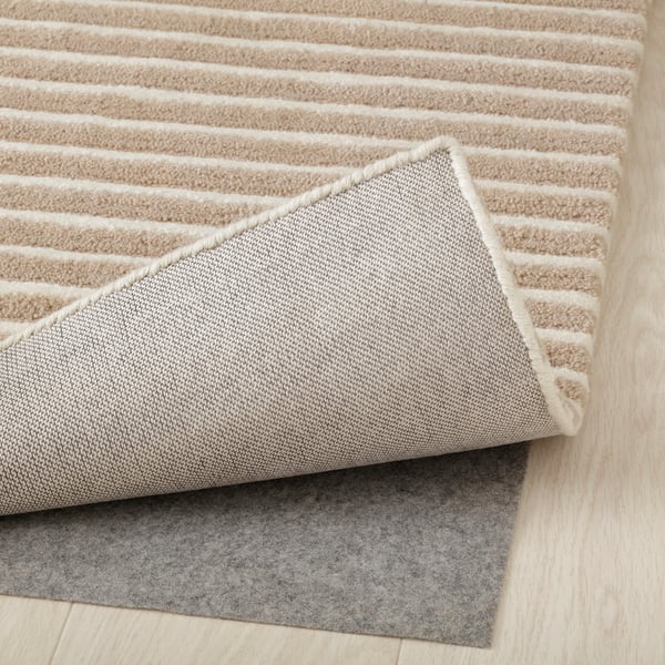 Rug corner reveals plush, striped design with felt backing for grip.
