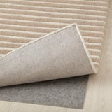 Rug corner reveals plush, striped design with felt backing for grip.