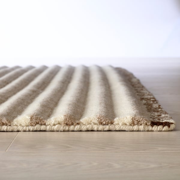 Close-up of a soft, plush rug with gentle stripes and a textured edge, showcasing high-quality craftsmanship.