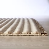 Close-up of a soft, plush rug with gentle stripes and a textured edge, showcasing high-quality craftsmanship.