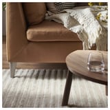 Couch on striped rug with coffee table and wine glass.