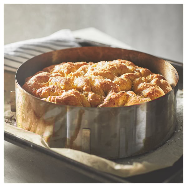 Silver baking ring holding golden-brown baked pastry with crispy top.