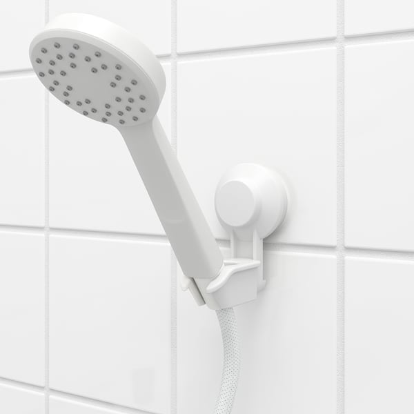 White shower head on holder, tilted down, suction-cup mounted on tiled wall, easy to attach and remove.
