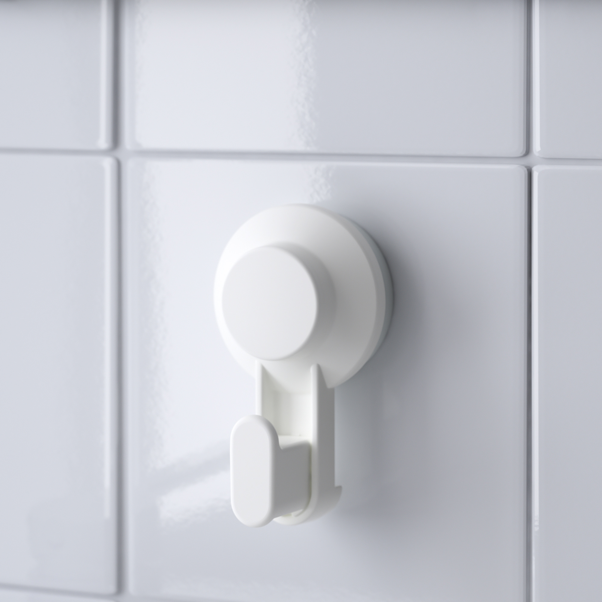 A single white TISKEN hook firmly attached to a tiled wall, showcasing its sturdy and sleek design.