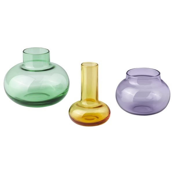 Three colorful glass vases in green, yellow, and purple, each with unique shapes, arranged together.