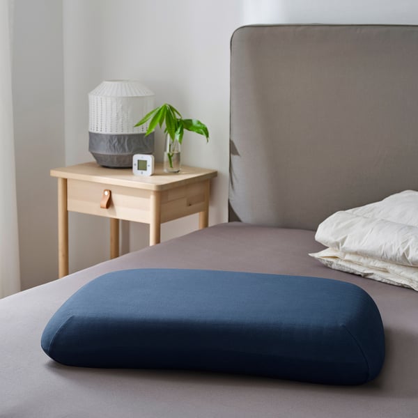 Blue ergonomic pillow on a bed, headrest visible.