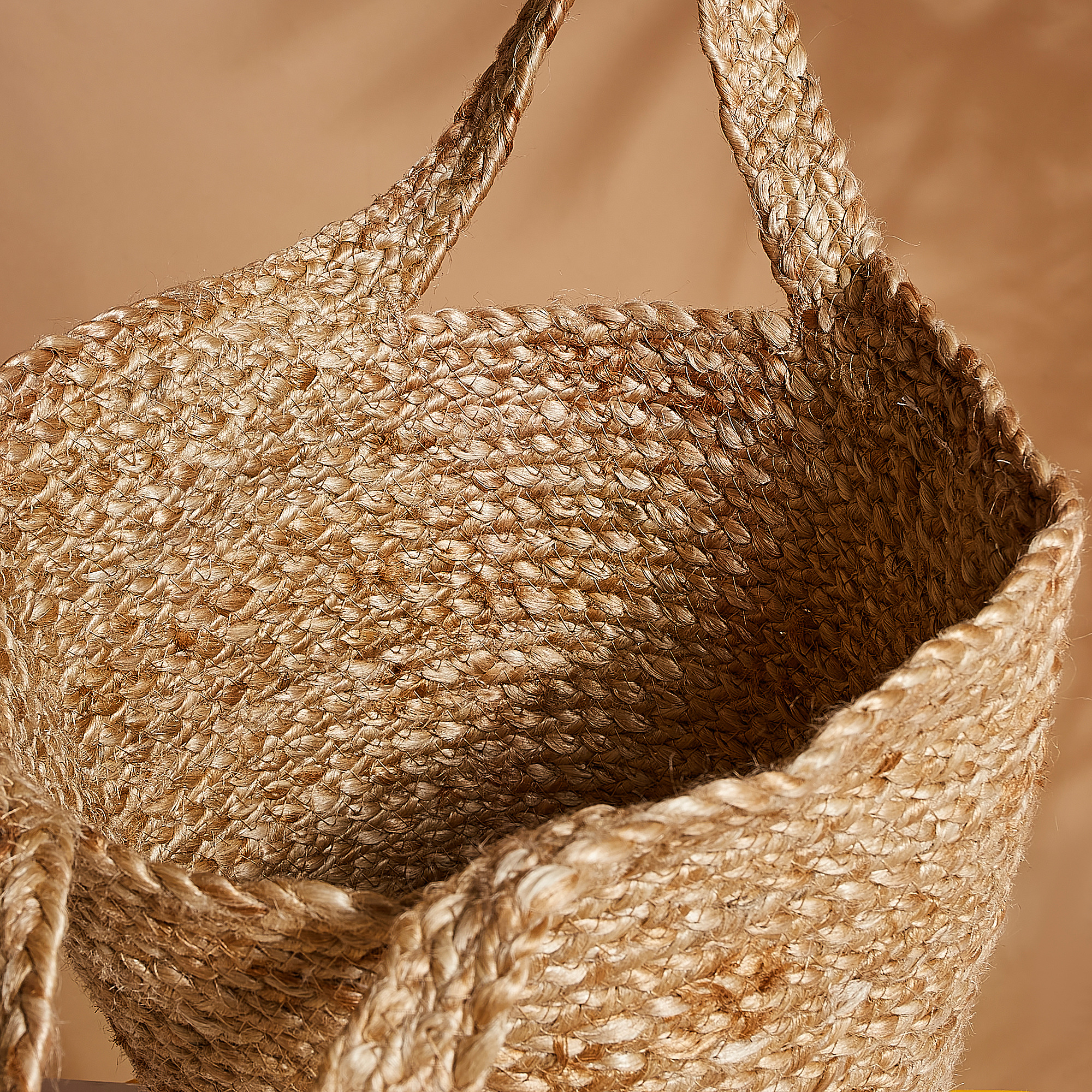 Handcrafted jute basket, braided with natural fibers, showcasing warm textures and sturdy handles.