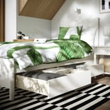 Modern bed with drawers, off-white. Green leaf bedding, coffee tray, open drawer under soft close.
