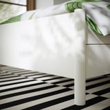 Close-up of TONSTAD bed frames sturdy, smooth white leg and drawer, showing quality finish and design.