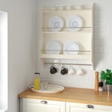 Kitchen shelf unit with white plates, cups, and juice bottle. Lightwood counter with tray. Compact, neat design.