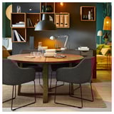 Modern dining set with TOSSBERGreen chairs and wooden table, stylishly arranged in a cozy room.