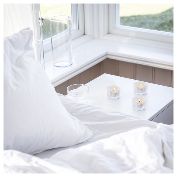 White bedroom with candles; crisp, clean décor. Lighted candles on window sill, soft ambiance.