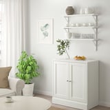 Minimalist living room with TRANHULT shelf, dishes, vase, plant, and fruit.