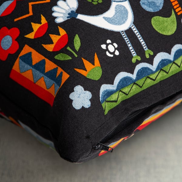 Colorful cushion cover with floral, bird, and human patterns, featuring a hidden zipper.