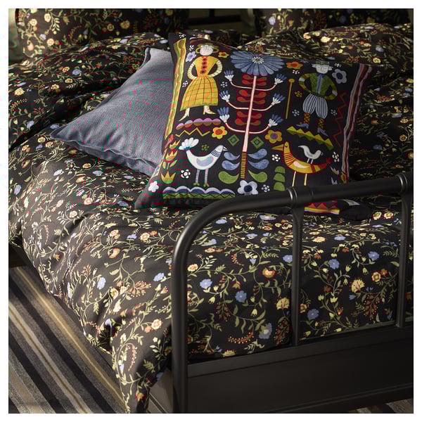Black bed with floral patterns & swedish pillow.