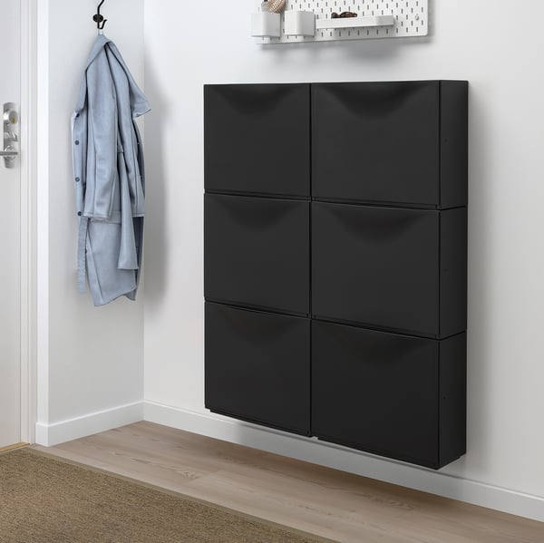 Black TRONES cabinet offers shallow storage, ideal for small spaces. Holds wall hook with blue jacket.