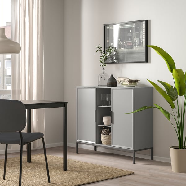 Grey metal sideboard with glass doors in modern living room.