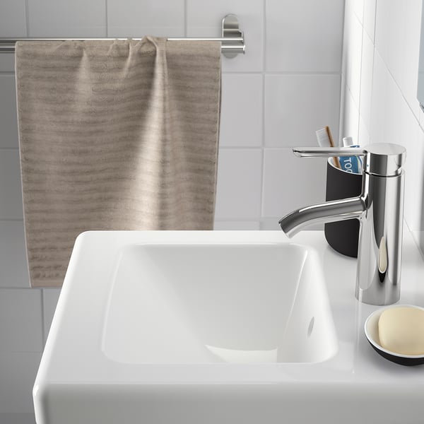 Modern bathroom with TVÄLLEN sink, chrome tap, towel, and toothbrush holder.