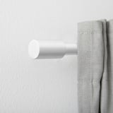 White finials on curtain rod, minimalist design.