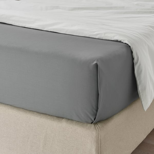 Close-up of neatly tucked gray bed sheet on a bed, showcasing its smooth, soft texture and precise fit.