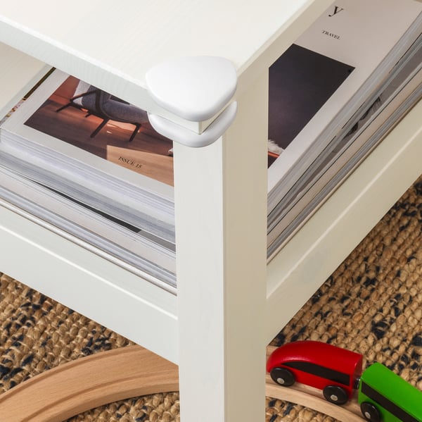 White corner bumpers attached to table edges for child safety.