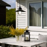 Black UPPLID lamp with glass shade, yellow flowers, outdoors. Classic, rustic design.