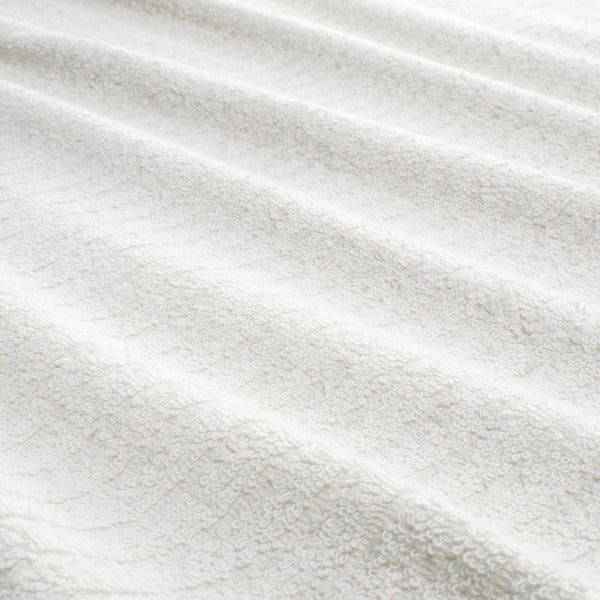 Close-up of soft, textured white towel showcasing its absorbent terry fabric with woven stripe patterns for quick drying.