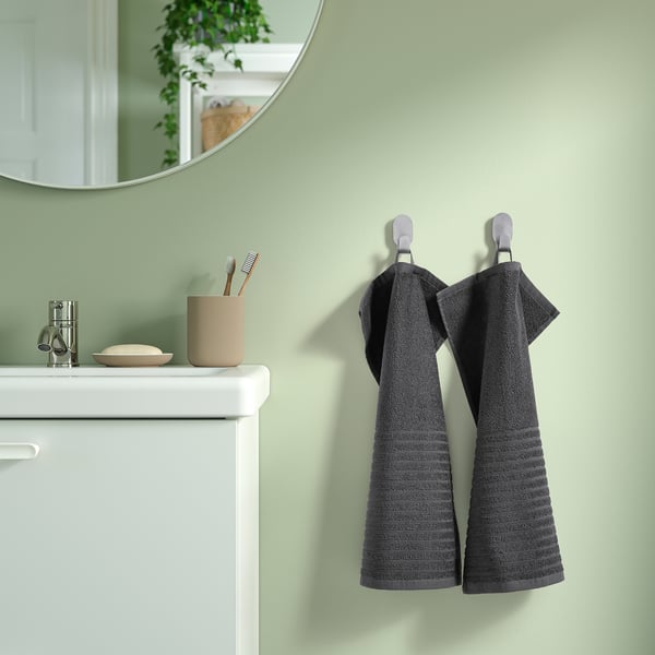 Gray striped cotton towels on hooks by white sink