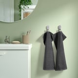 Gray striped cotton towels on hooks by white sink