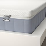 Close-up of IKEA VALEVÅG mattress: white topper, blue-gray base, labels visible.