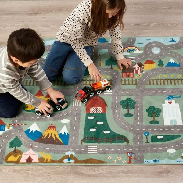 Kids playing with toy cars on a colorful rug with roads, houses, and nature scenes; anti-slip underside.