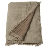 A beige VALLKRASSING cotton throw blanket with a textured, crinkled design and frayed edges.