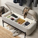 Organized storage bench with open lid revealing divided compartments filled with accessories. Hinged lid supported by gas spring for easy access.