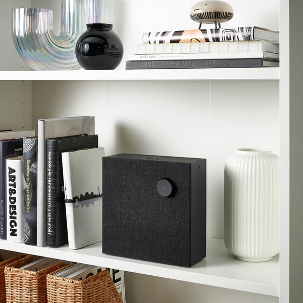 Bookshelf with black speaker, white vase, and decorative items.