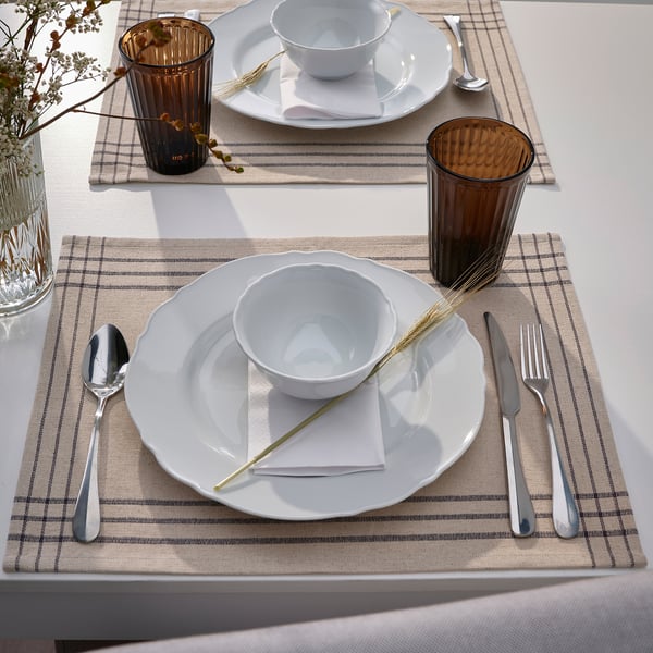 Two table settings with white dishes, silverware, brown cups, and beige place mats.
