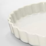 Smooth, white pie dish with wavy edges, clean design, made of glossy stoneware.