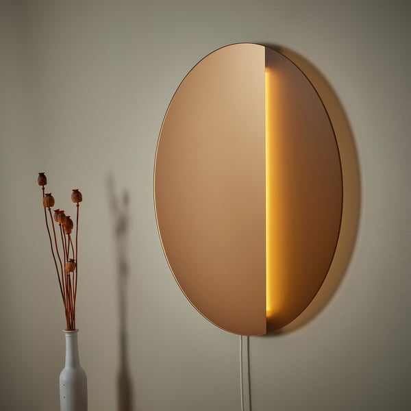 Wall-mounted light with bronze glass, warm light, mirrored reflection.