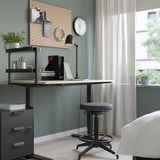 Home office with VATTENKAR shelf, laptop, books, lamp, stool, pegboard, and window.