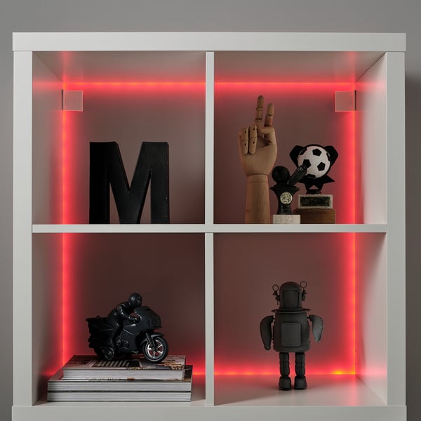 White shelf with red led lit sides. Items include black m, wooden hand, soccer trophy, motorcycle model, robot toy, and book stack.