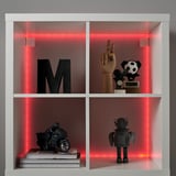 White shelf with red led lit sides. Items include black m, wooden hand, soccer trophy, motorcycle model, robot toy, and book stack.
