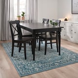 Blue floral rug under black dining table with chairs.