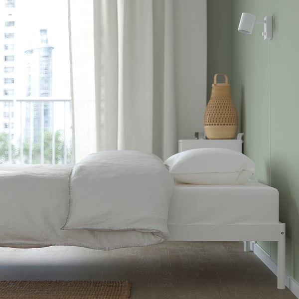White VEVELSTAD bed frame with metal slats. Modern decor and wicker basket.