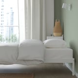 White VEVELSTAD bed frame with metal slats. Modern decor and wicker basket.