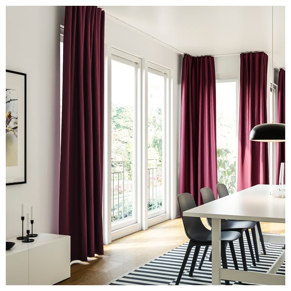 Bright dining room with white table, black chairs, striped rug, maroon VIDGA curtains on minimalistic rail, large windows, nature view outside.